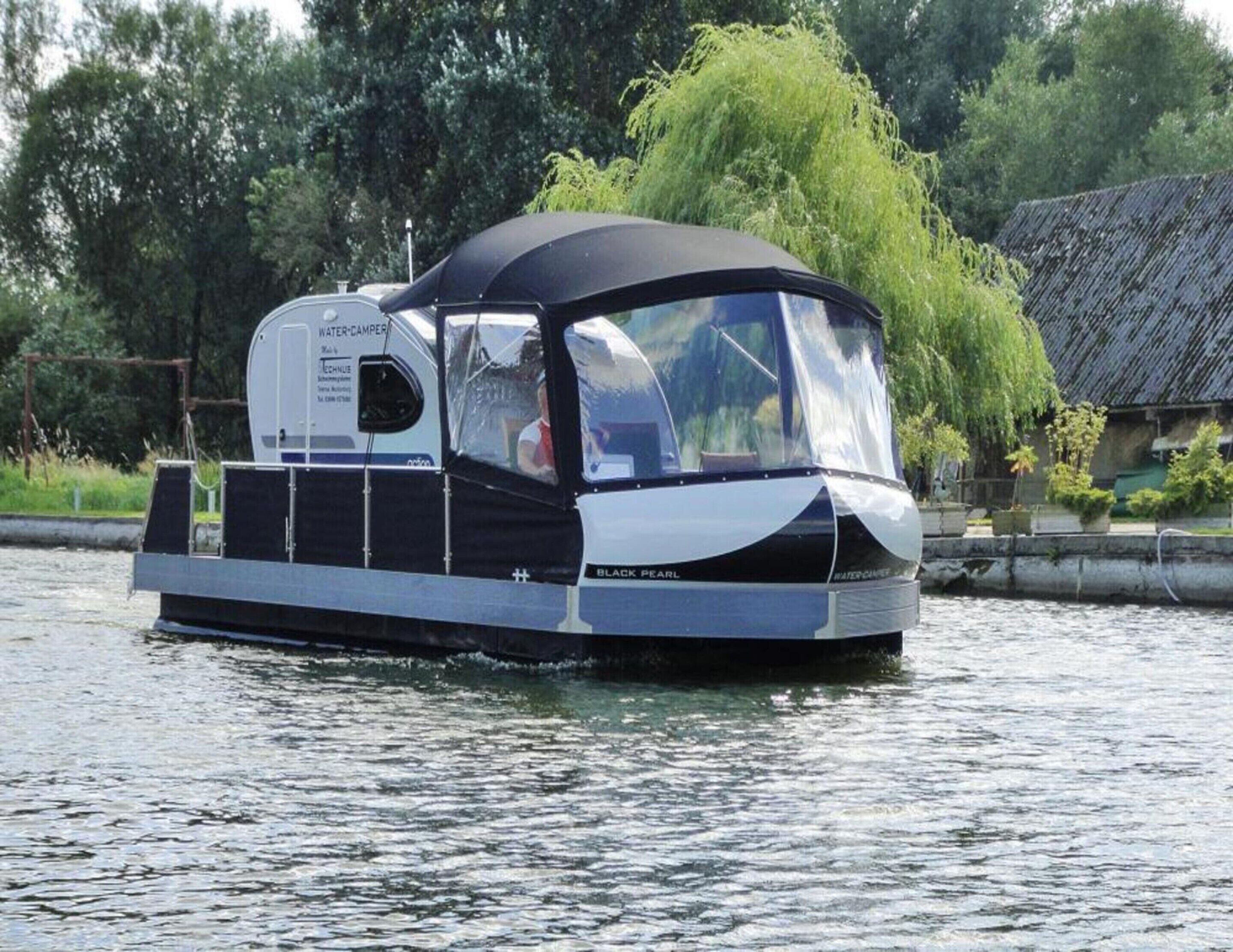 A watercraft with a covered cabin, a water-camper, and the name "BLACK PEARL" on the side.