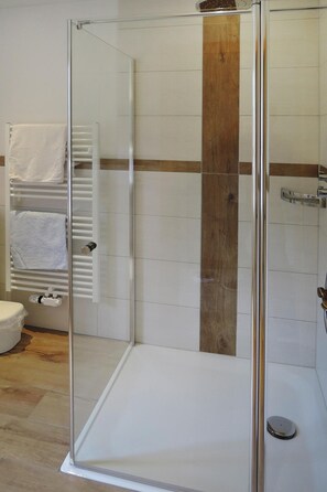 Bathroom features a glass-enclosed shower area with a wooden panel accent and a towel rack.