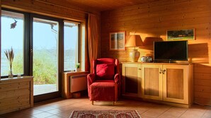 A cozy room with wooden walls, a red chair, a television, and a cabinet. - Doppelhaushalfte in Hasselfelde (Oberharz am Brocken)