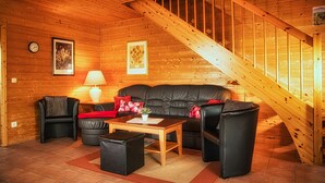 A cozy log cabin interior with a wooden staircase, leather furniture, and a fireplace. - Doppelhaushalfte in Hasselfelde (Oberharz am Brocken)