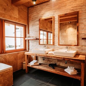 A modern bathroom with two sinks, wooden vanity, and large windows.