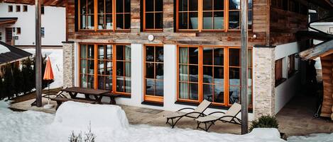 A two-story log cabin with large windows and a covered patio area.