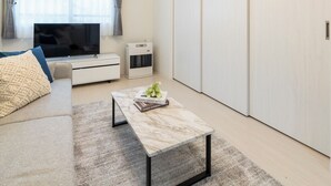 A modern living room with a flat-screen TV, a sofa, a coffee table, and a sliding closet door. - UNION 201 (Sapporo)