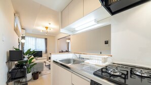 A modern kitchen with a built-in stove, a sink, and a dining area with a table and chairs. - UNION 201 (Sapporo)