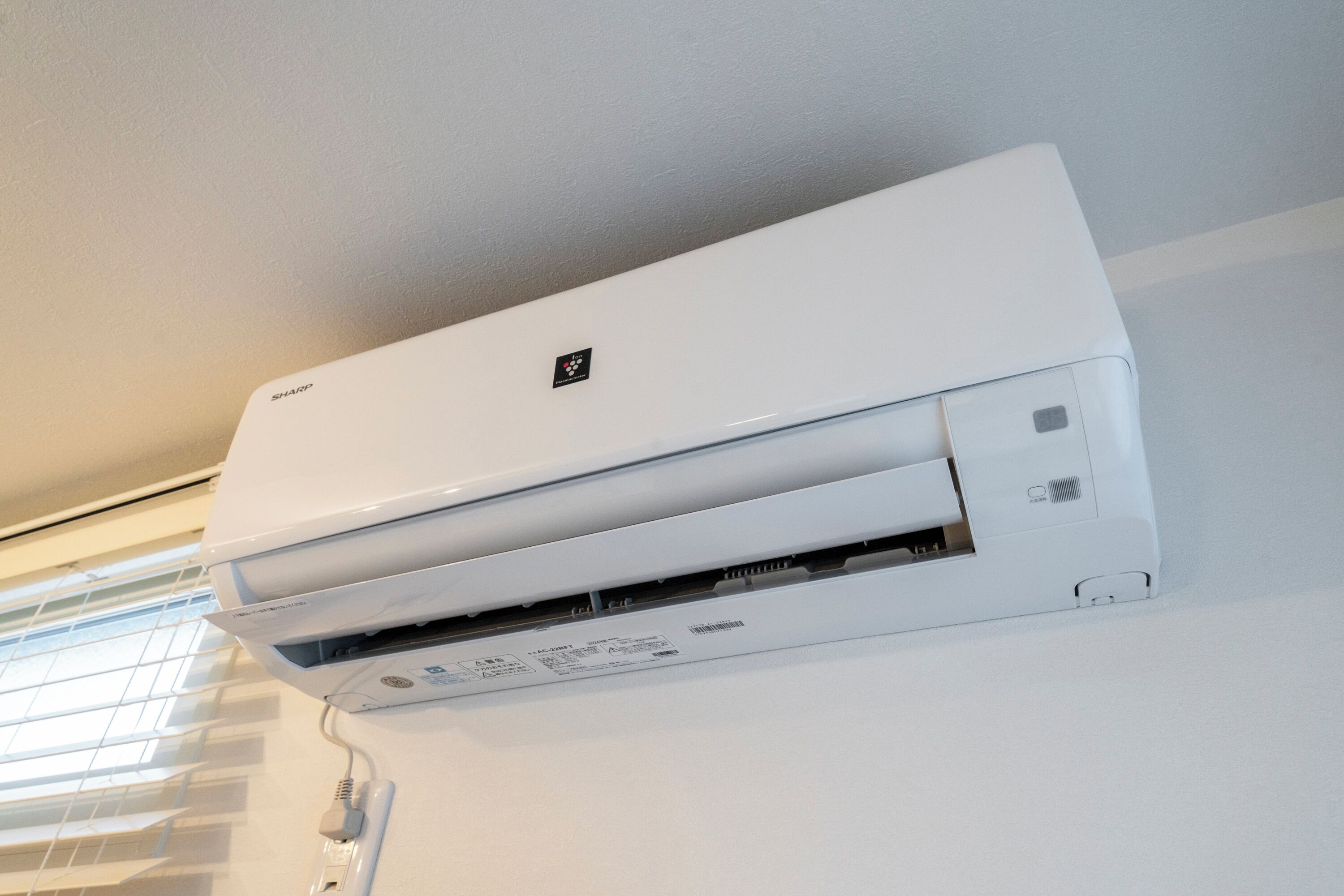 A white wall-mounted air conditioner with a control panel and a brand logo.