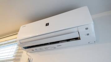 A white wall-mounted air conditioner with a control panel and a brand logo.
