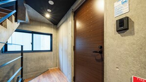 A modern interior with a wooden door, a fire alarm, and a staircase. - UNION 201 (Sapporo)