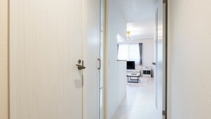 A hallway with a door leading to a room with a bed, a desk, and a TV. - UNION 201 (Sapporo)