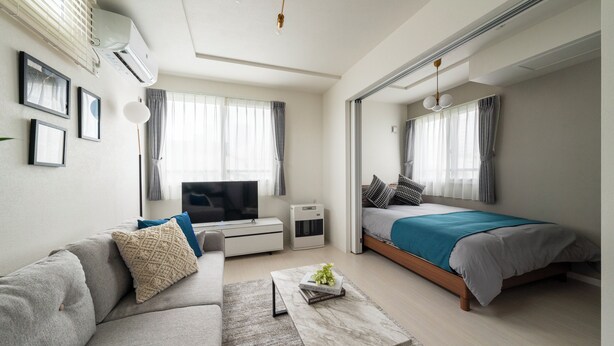 A modern hotel room with a sofa, a bed, a television, and a desk. - UNION 201 (Sapporo)