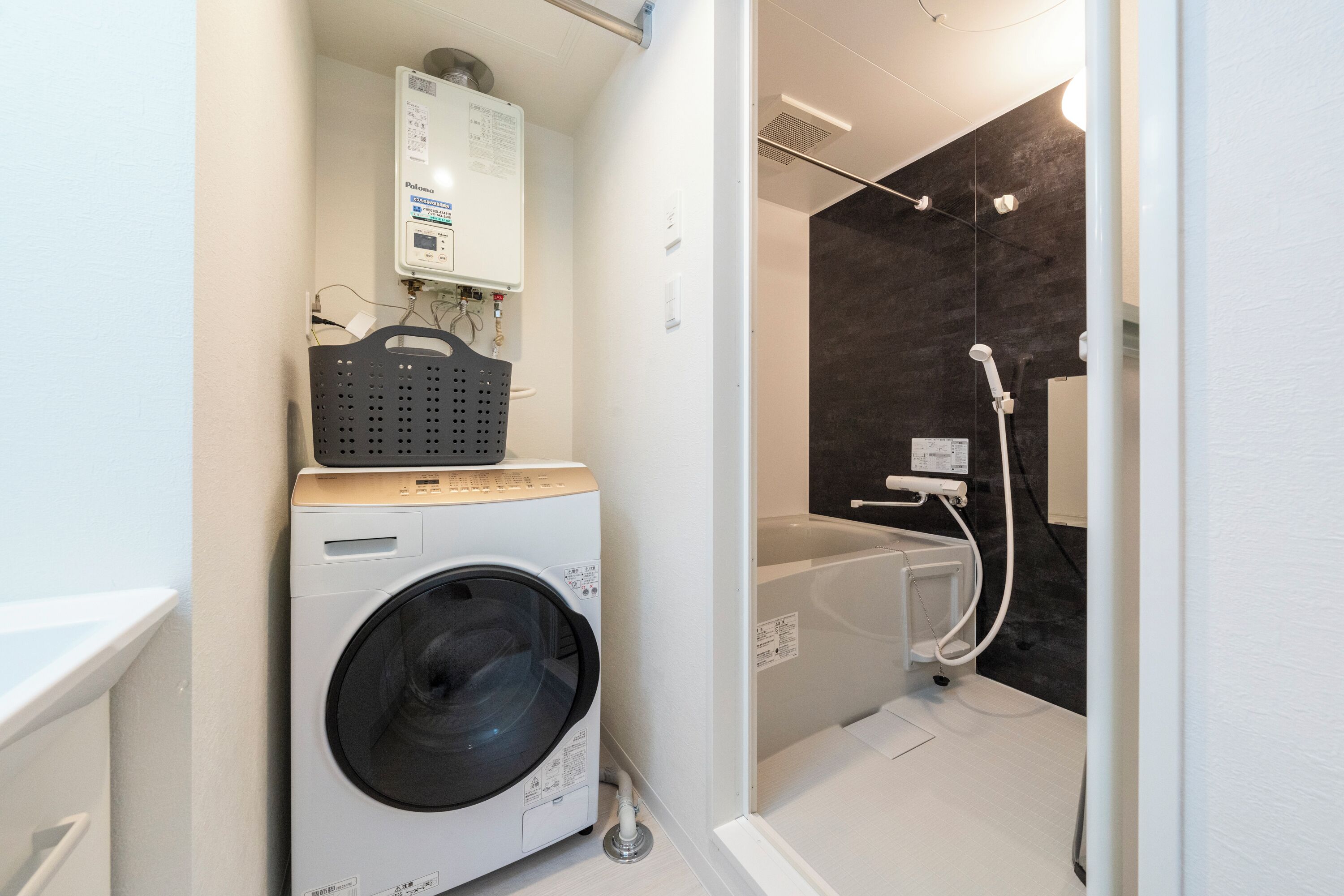 A compact laundry area with a washing machine, a drying rack, and a shower.