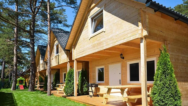 En rad med trähus med en inglasad veranda, ett picknickbord och en grill.