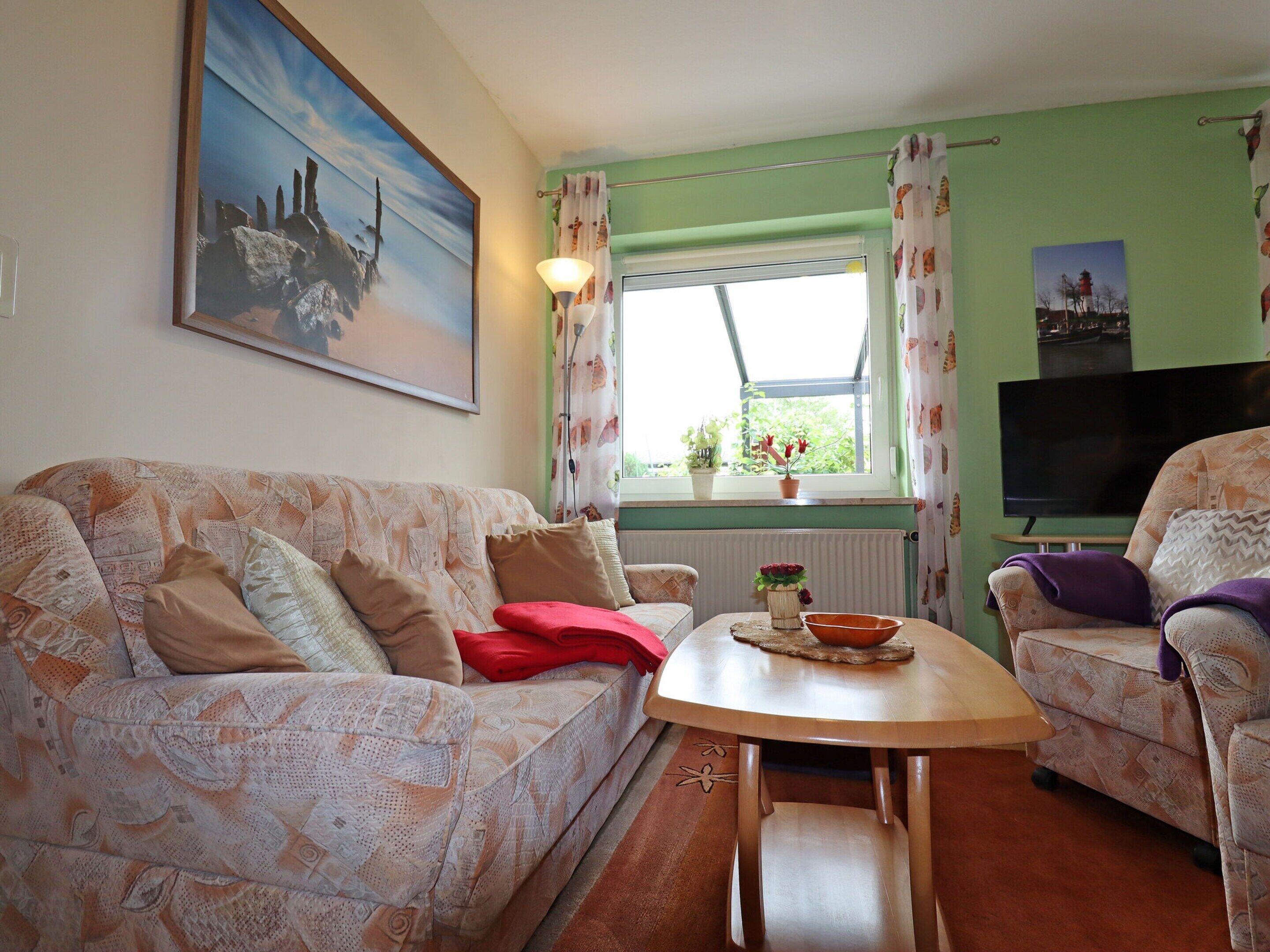 A living room with a patterned sofa, a small wooden table, and a television.