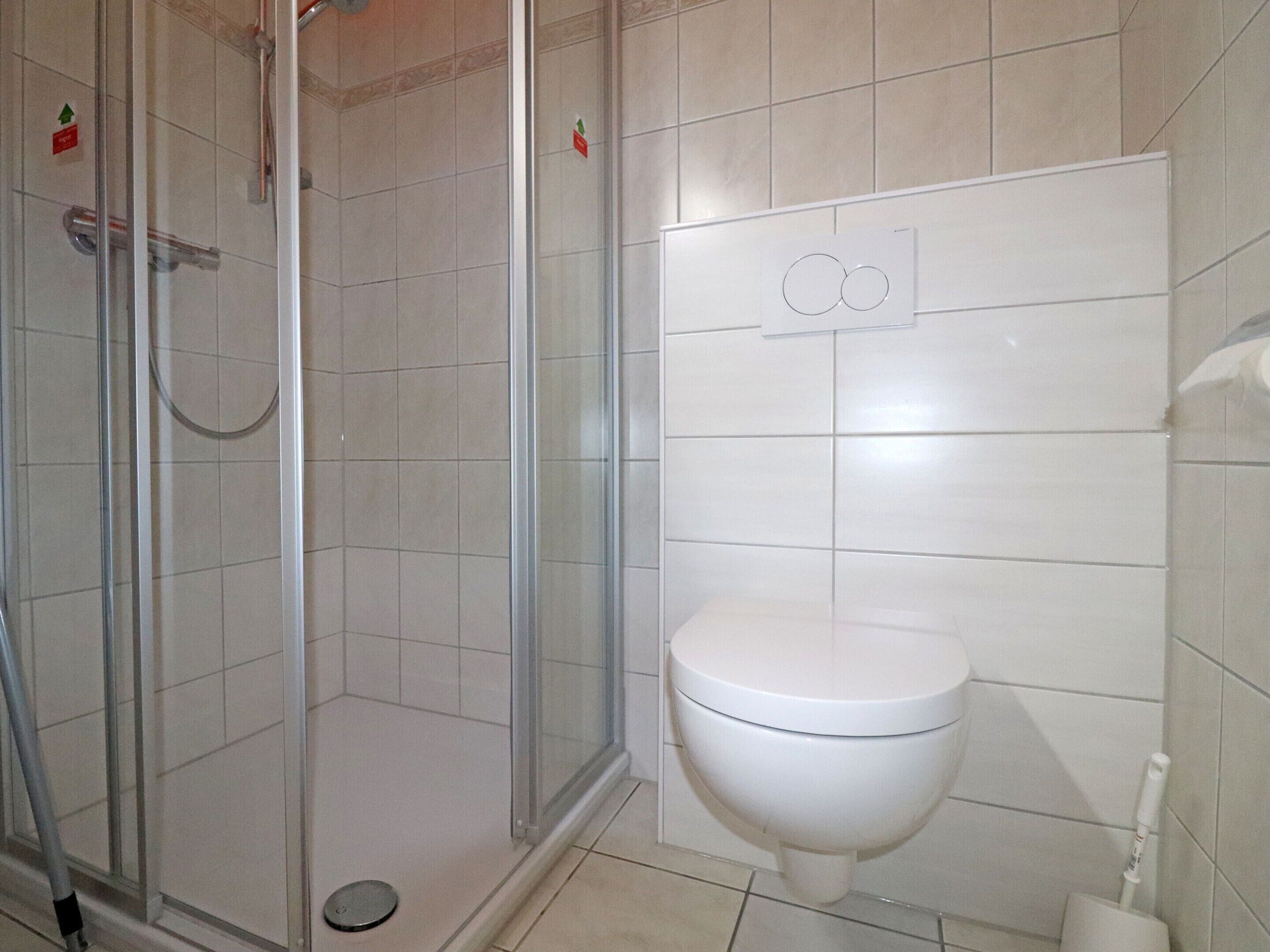 A bathroom with a glass-enclosed shower, a toilet, and a bidet.