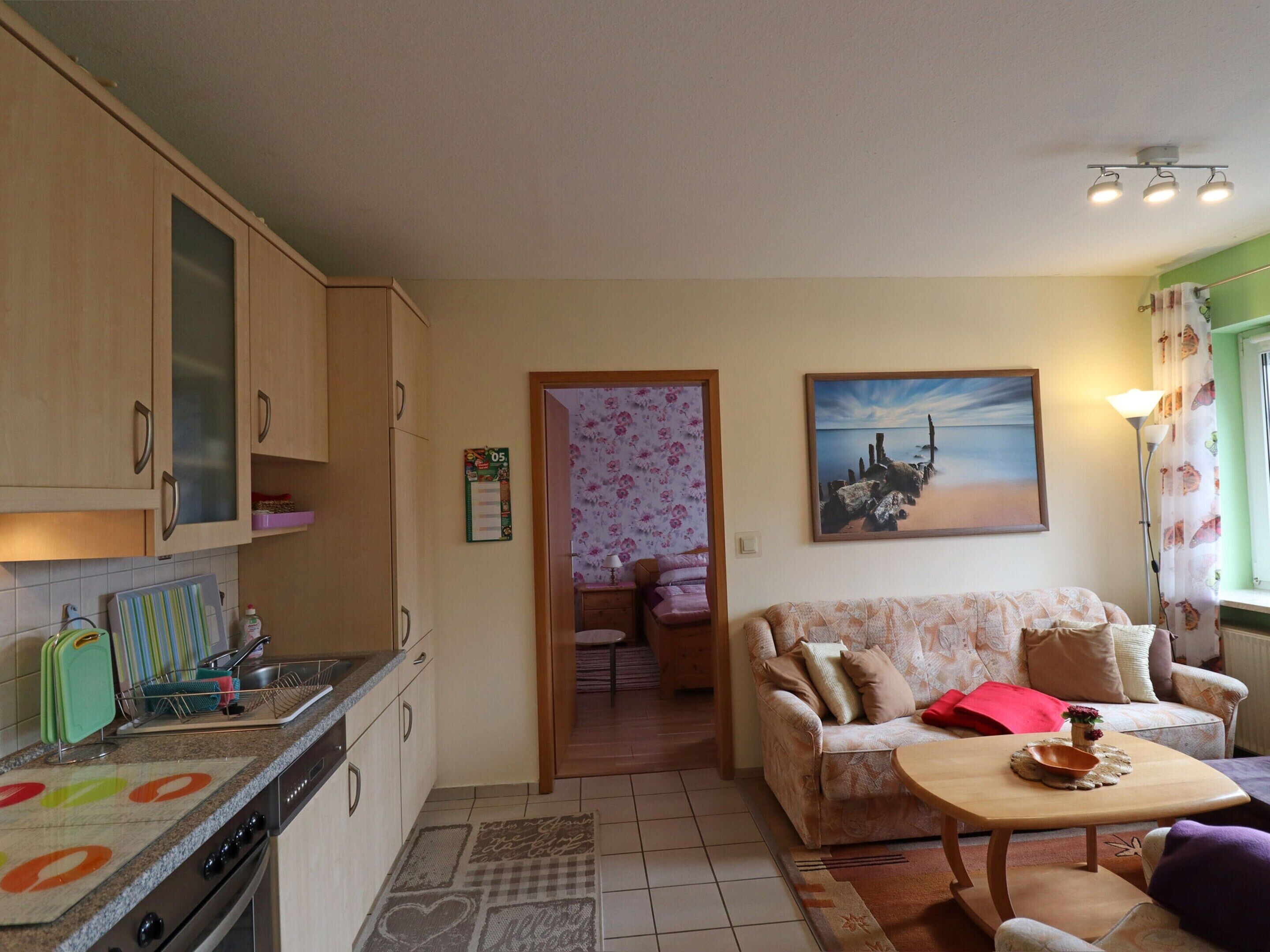 A compact living space with a kitchen, a sofa, and a dining area.