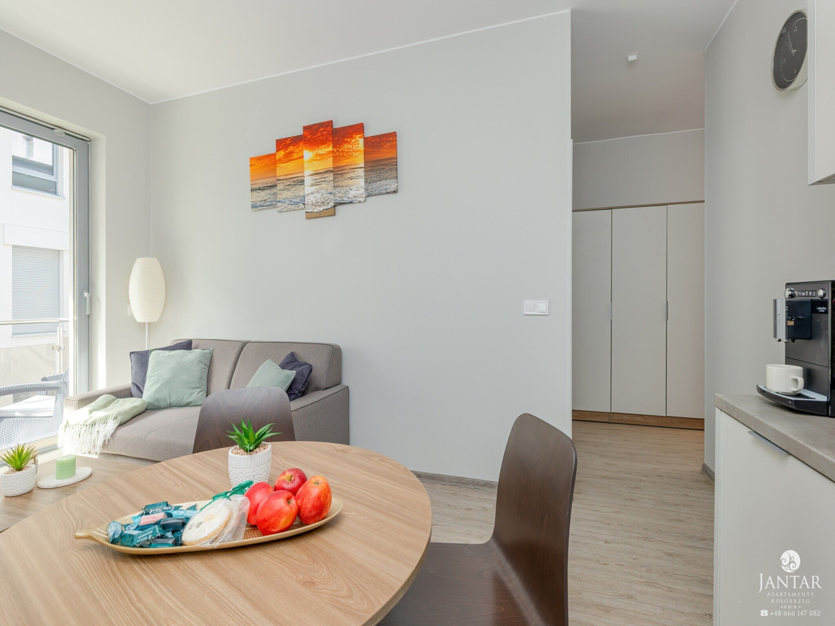 Una sala de estar moderna con una mesa de comedor redonda, un sofá y una zona de cocina con una cafetera.