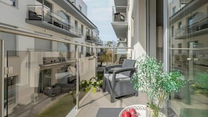 A modern apartment with a glass balcony, outdoor seating, and a view of neighboring buildings. - Apartment in Pobierowo Near Baltic Beach (Rewal)