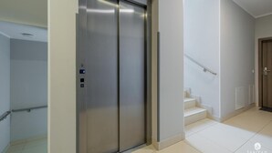 A modern elevator with a metallic finish, a handrail, and a control panel with buttons. - Apartment in Pobierowo Near Baltic Beach (Rewal)