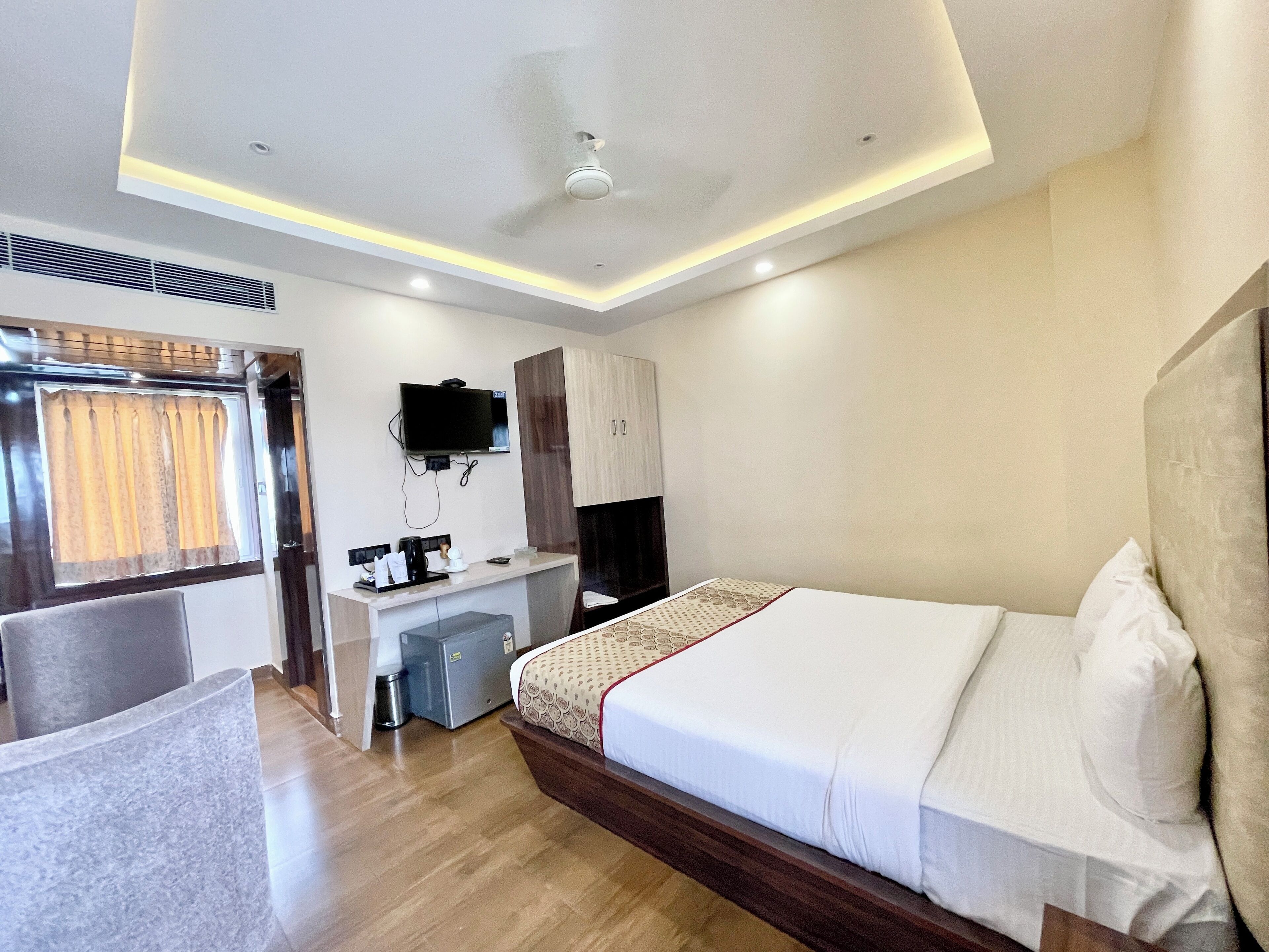 A modern hotel room with a bed, desk, chair, and a television.