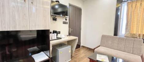 Un salon moderne doté d’un téléviseur à écran plat, d’une petite kitchenette, d’un canapé et d’une table basse.