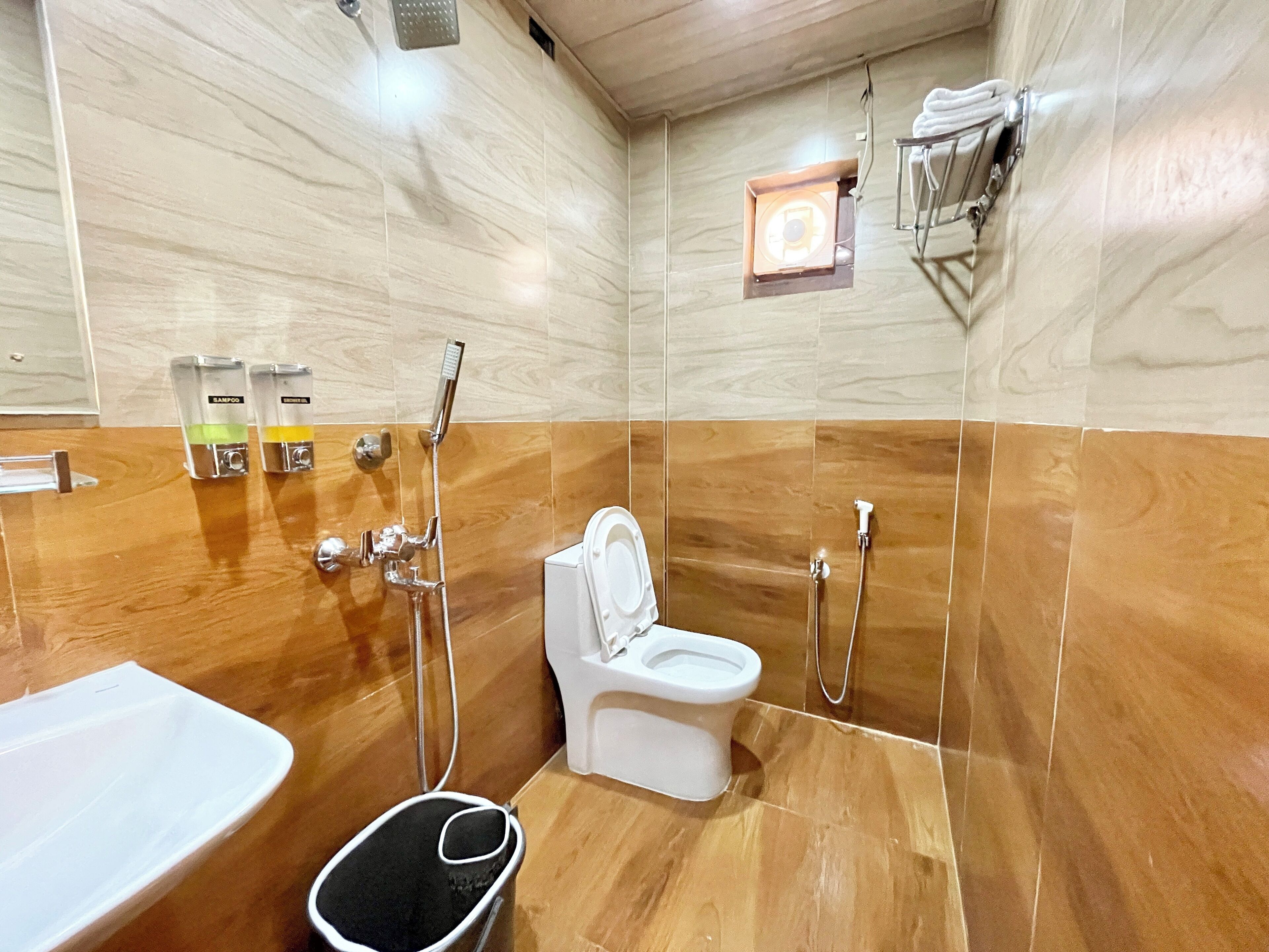 A modern bathroom with a wooden floor, a white toilet, a shower area, and a sink.