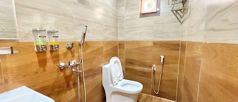 A modern bathroom with a wooden floor, a white toilet, a shower area, and a sink.