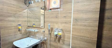 Un baño con pared de madera, un lavabo, un espejo, una ducha y un inodoro.