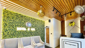 A hotel reception area with a green wall, a reception desk, and a sofa. - A One Pride - Puri near Sea Beach (Puri)