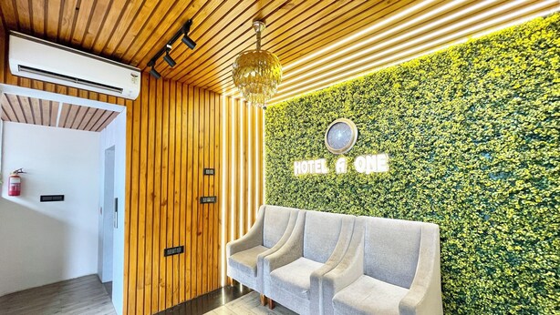A reception area with a wooden ceiling, a green wall with 'HOTEL A ONE' signage, and a grey sofa. - A One Pride - Puri near Sea Beach (Puri)