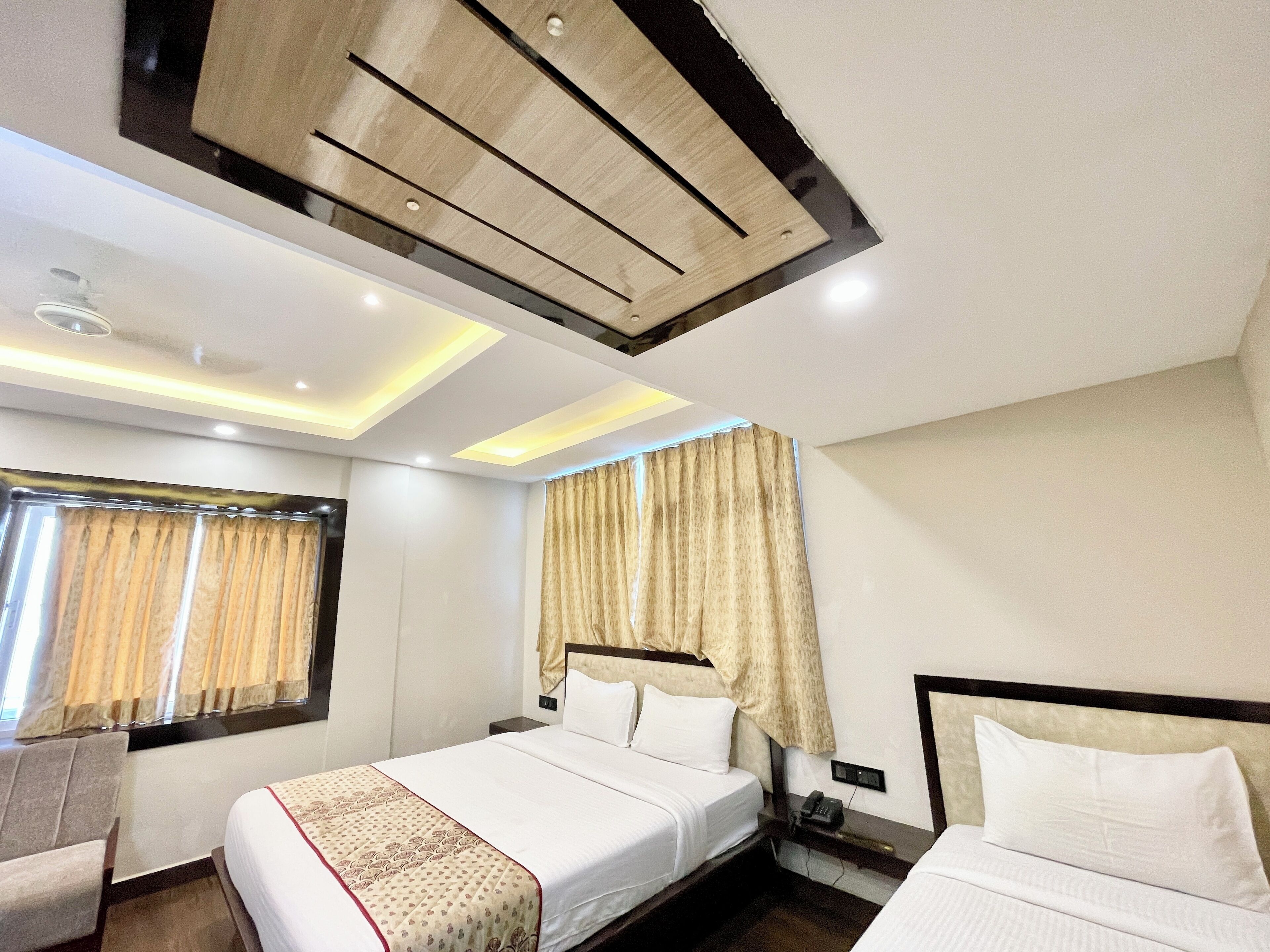 A hotel room with a bed, a bedside table, a chair, and a window with curtains.