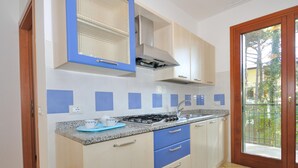 A kitchen with a gas stove, blue cabinets, and a window overlooking a garden.