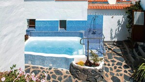 Une piscine aux carreaux de mosaïque bleus, un sentier en pierre et une vue sur la mer.