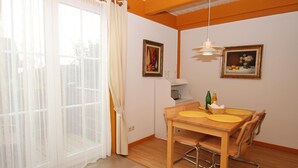 A dining area with a wooden table and chairs, a chandelier, and two framed paintings on the wall. - Appartementhaus auf Pellworm (Pellworm)