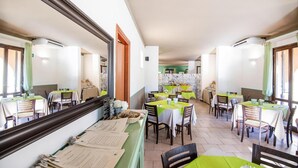 A restaurant with multiple tables and chairs, a counter with menus, and a green and white color scheme. - Residence Le Corti di Montepitti, Suvereto (Suvereto)