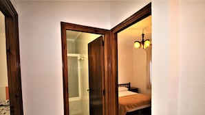 Quarto com cama, porta de madeira e área de chuveiro.