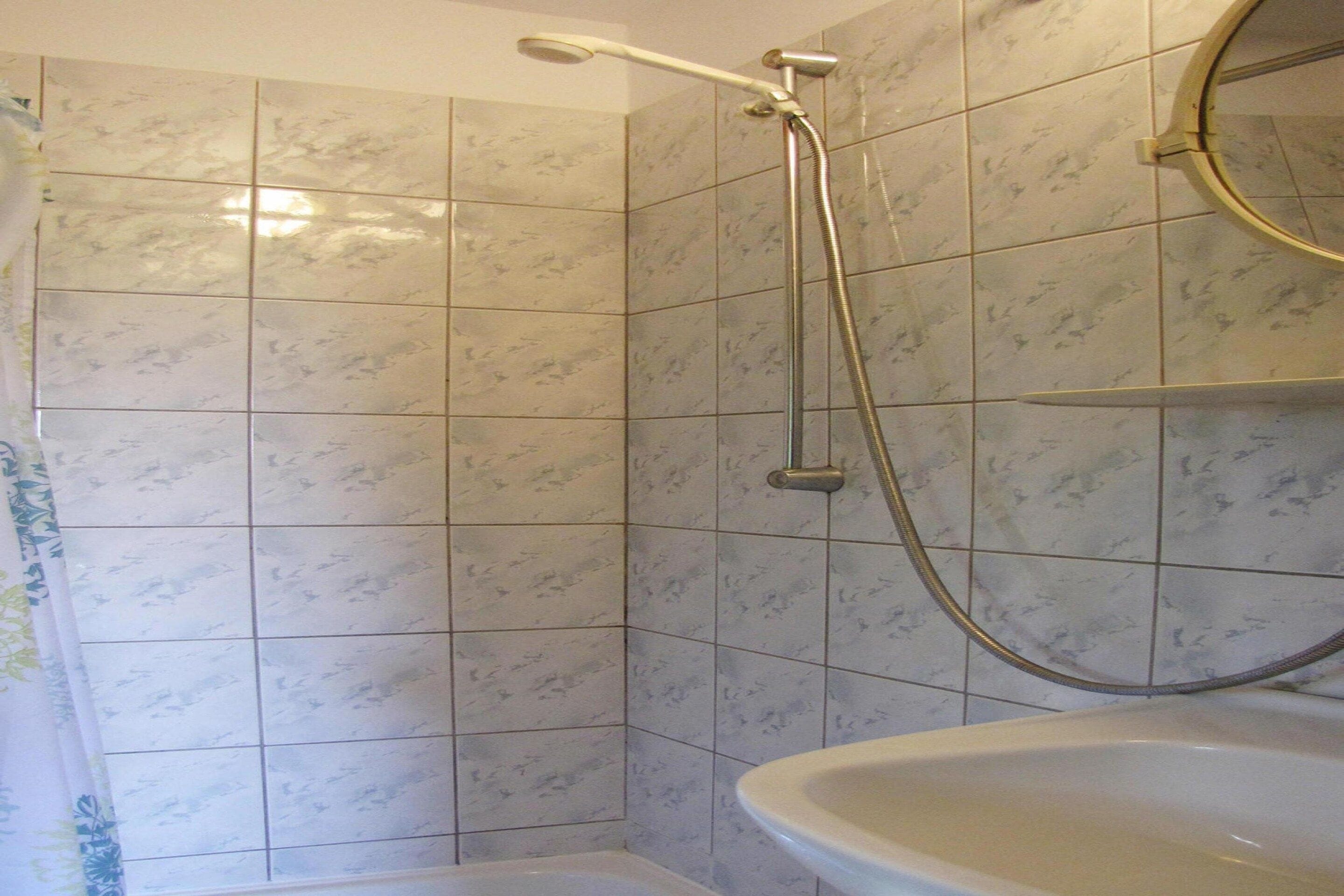 A bathroom with a shower, a sink, and tiled walls.
