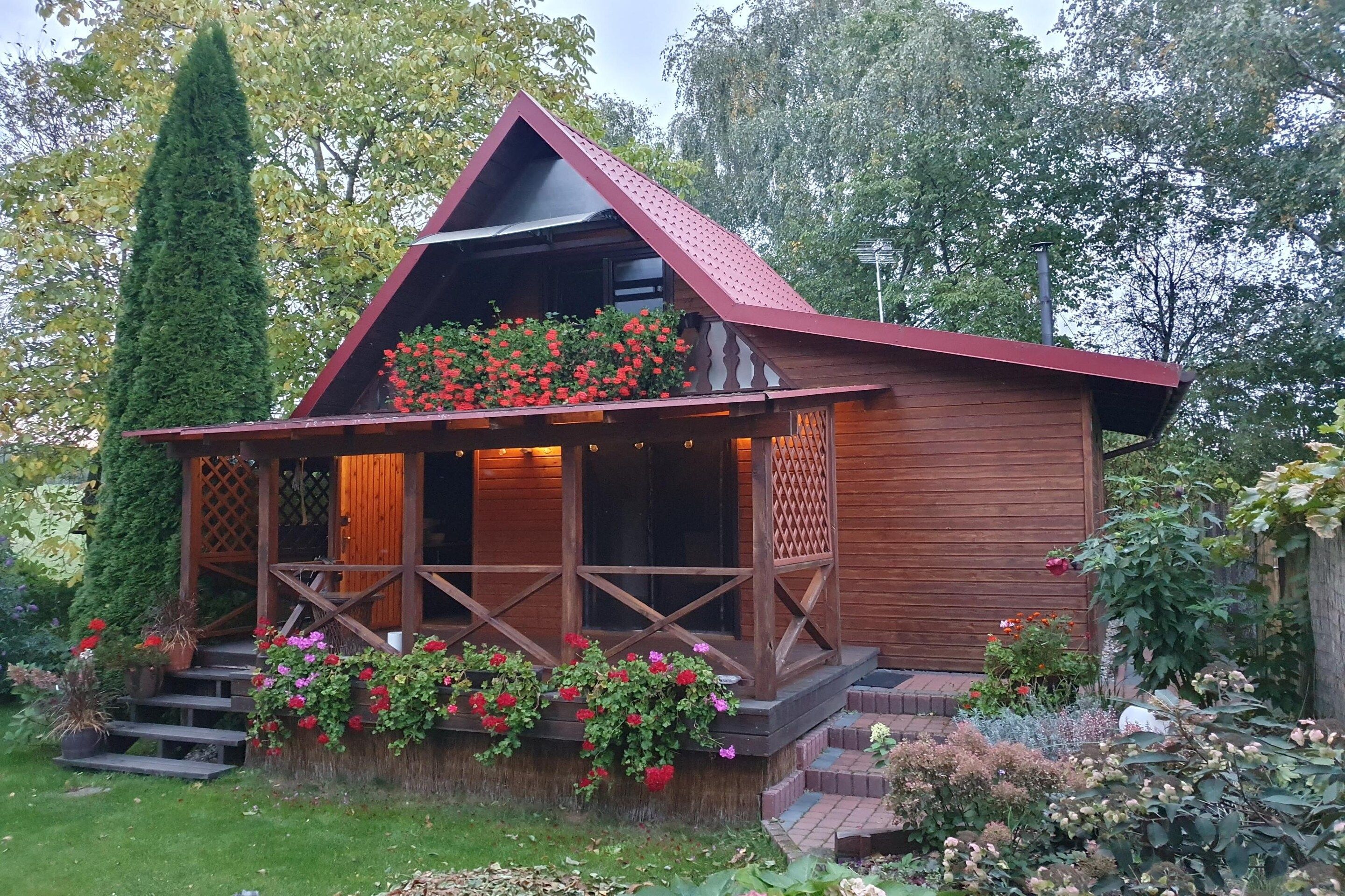 A wooden cabin with a sloped roof, a porch with railings, and a staircase leading to the entrance.