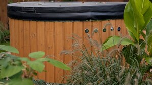 A hot tub with a wooden exterior, surrounded by greenery. - Wooden House by Masurian Lakes Gizycko (Gizycko)