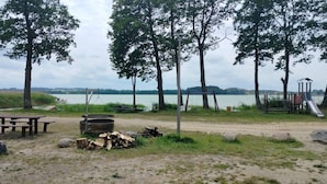 A lakeside park with picnic tables, a fire pit, and playground equipment. - Wooden House by Masurian Lakes Gizycko (Gizycko)