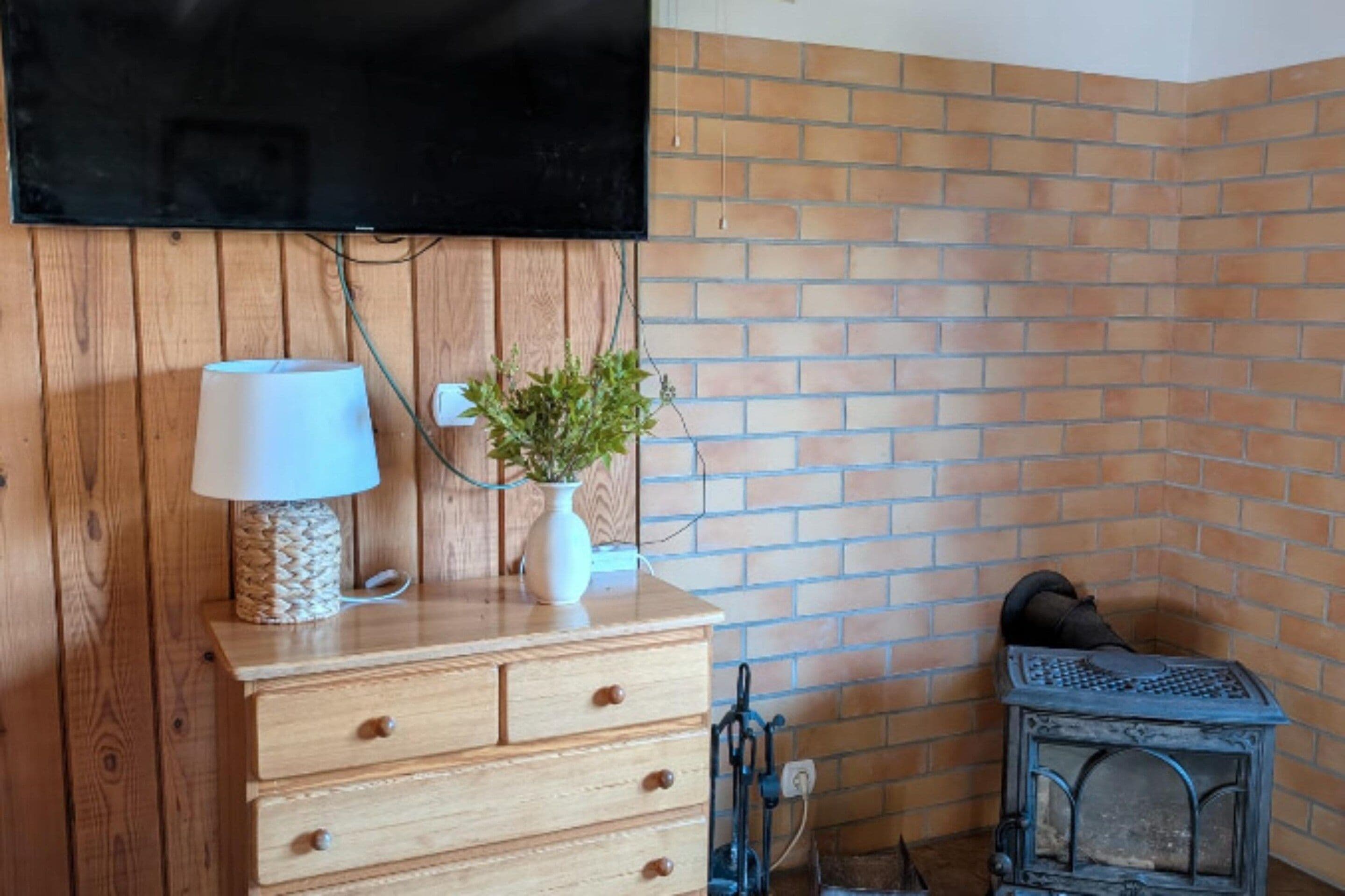 A wooden dresser with drawers, a lamp, and a vase with a plant.