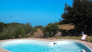 A rectangular swimming pool with a brick deck, surrounded by a wooden fence and trees. - Casa Mare Vallugola di Gabicce, Vallugola (Pesaro)