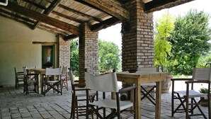 An outdoor patio with rustic wooden furniture and a brick chimney. - Casa Mare Vallugola di Gabicce, Vallugola (Pesaro)