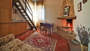 A cozy living room with a fireplace, wooden staircase, and a dining area. - Casa Mare Vallugola di Gabicce, Vallugola (Pesaro)