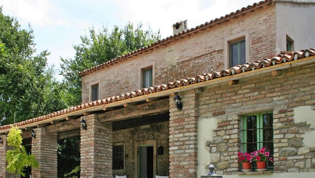 A rustic stone building with a tiled roof, outdoor seating, and potted plants. - Casa Mare Vallugola di Gabicce, Vallugola (Pesaro)