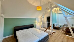 A bedroom with a bed, a skylight, a staircase, and a small seating area. - Ferienhaus Havelzeit in Werder an der Havel (Werder (Havel))