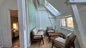 A compact attic room with a skylight, wooden furniture, and a view of the outside. - Ferienhaus Havelzeit in Werder an der Havel (Werder (Havel))