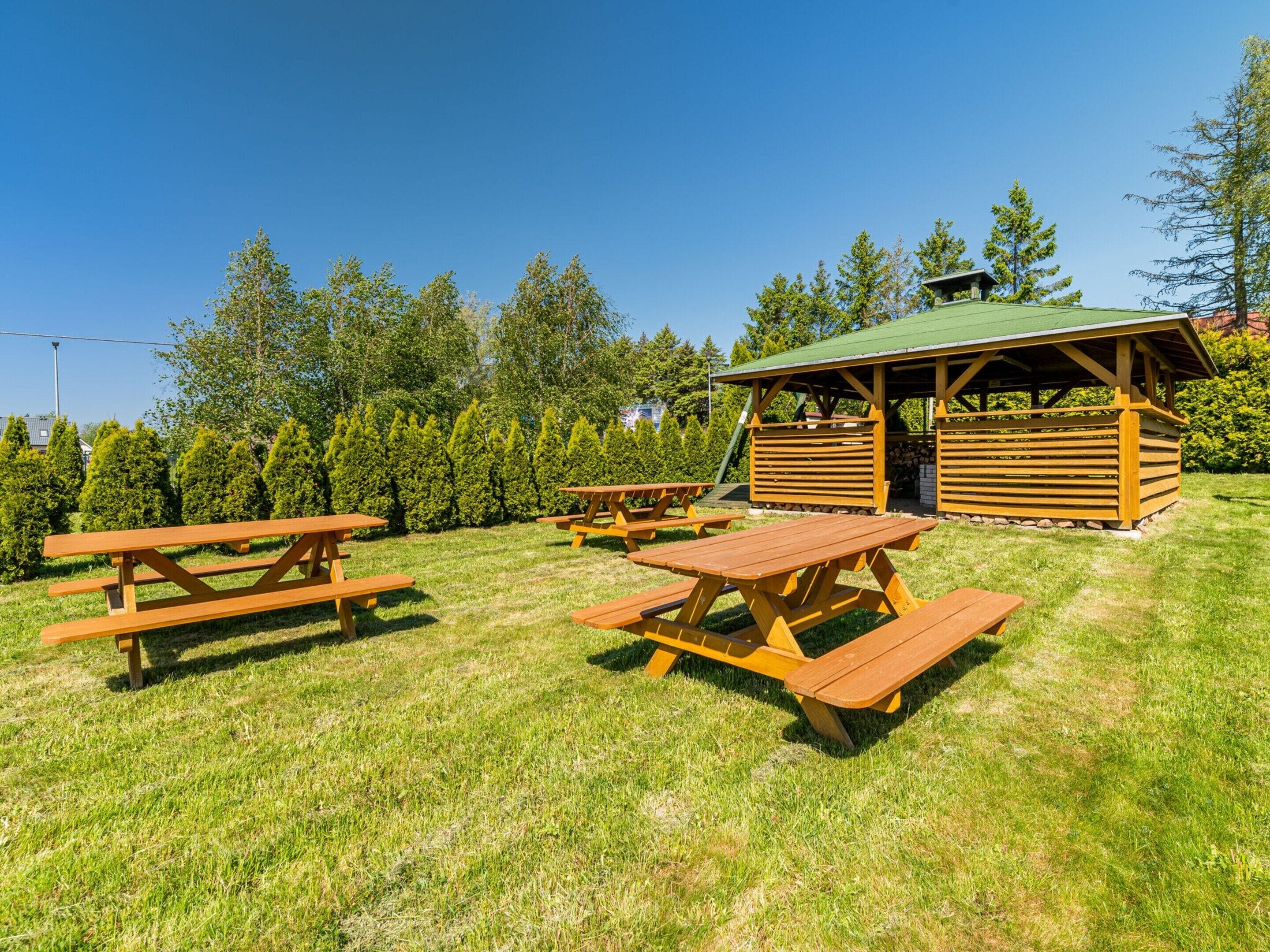 Ein Picknickbereich mit Holzbänken und einem überdachten Schutzhaus.