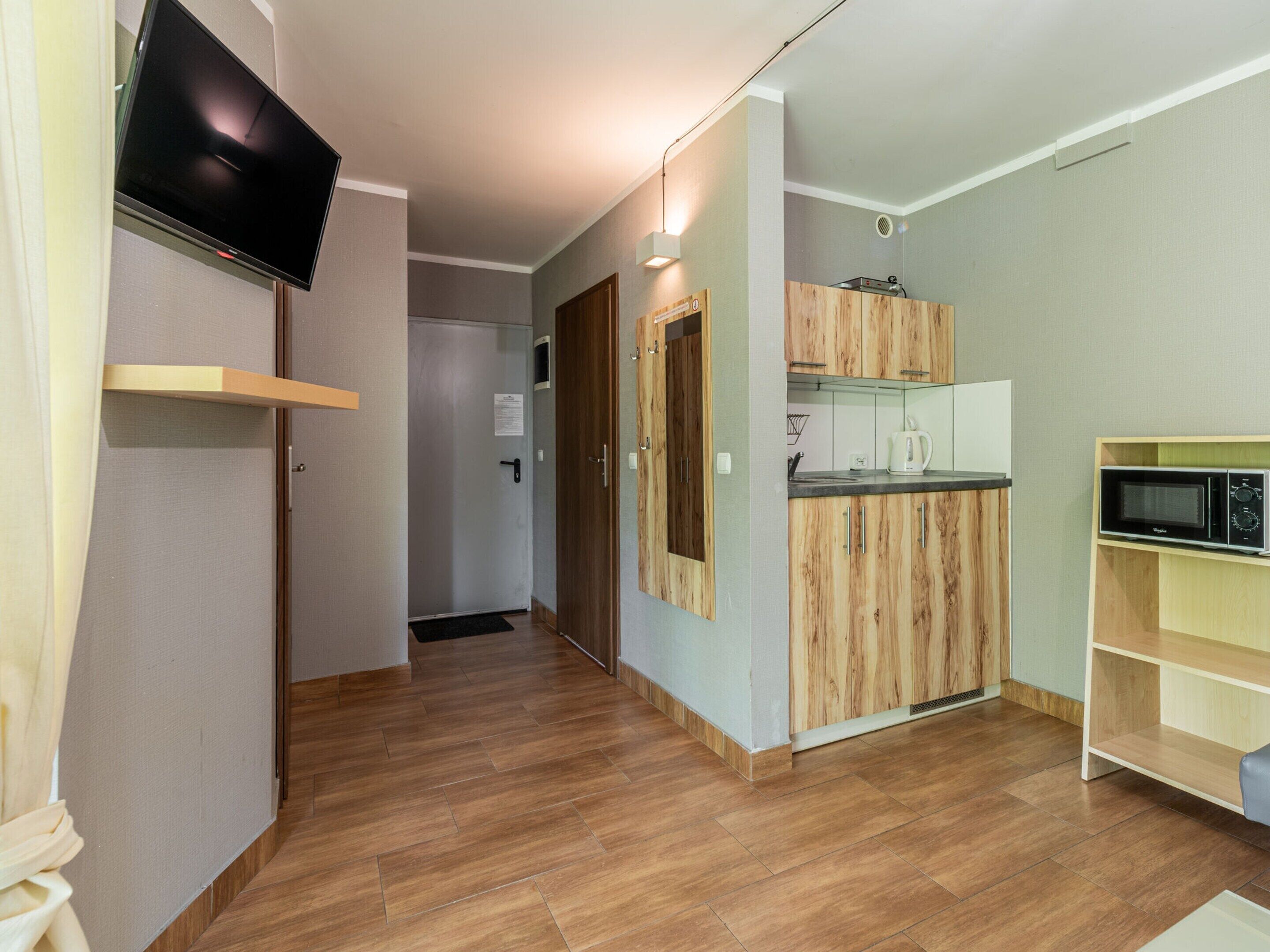 A modern kitchen with wooden cabinets, a microwave, and a coffee maker.