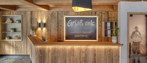 Un mostrador de recepción de madera con un cartel de pizarra que dice "GriaB enk" y "Art Resort Fugenhof Almendorf Zillertal".