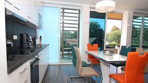 Une cuisine moderne avec un coin repas, de grandes fenêtres et une vue sur l’extérieur.