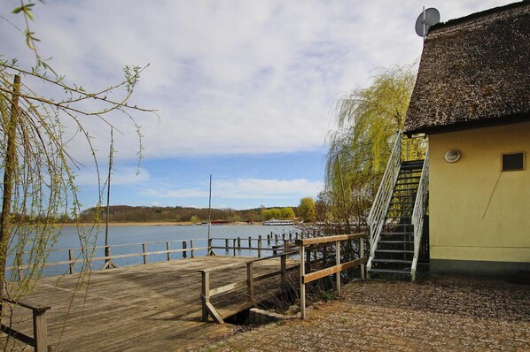 A wooden dock leading to a building with a satellite dish, overlooking a calm body of water. - Ferienwohnung am Krakower See, Krakow am See (Krakow am See)